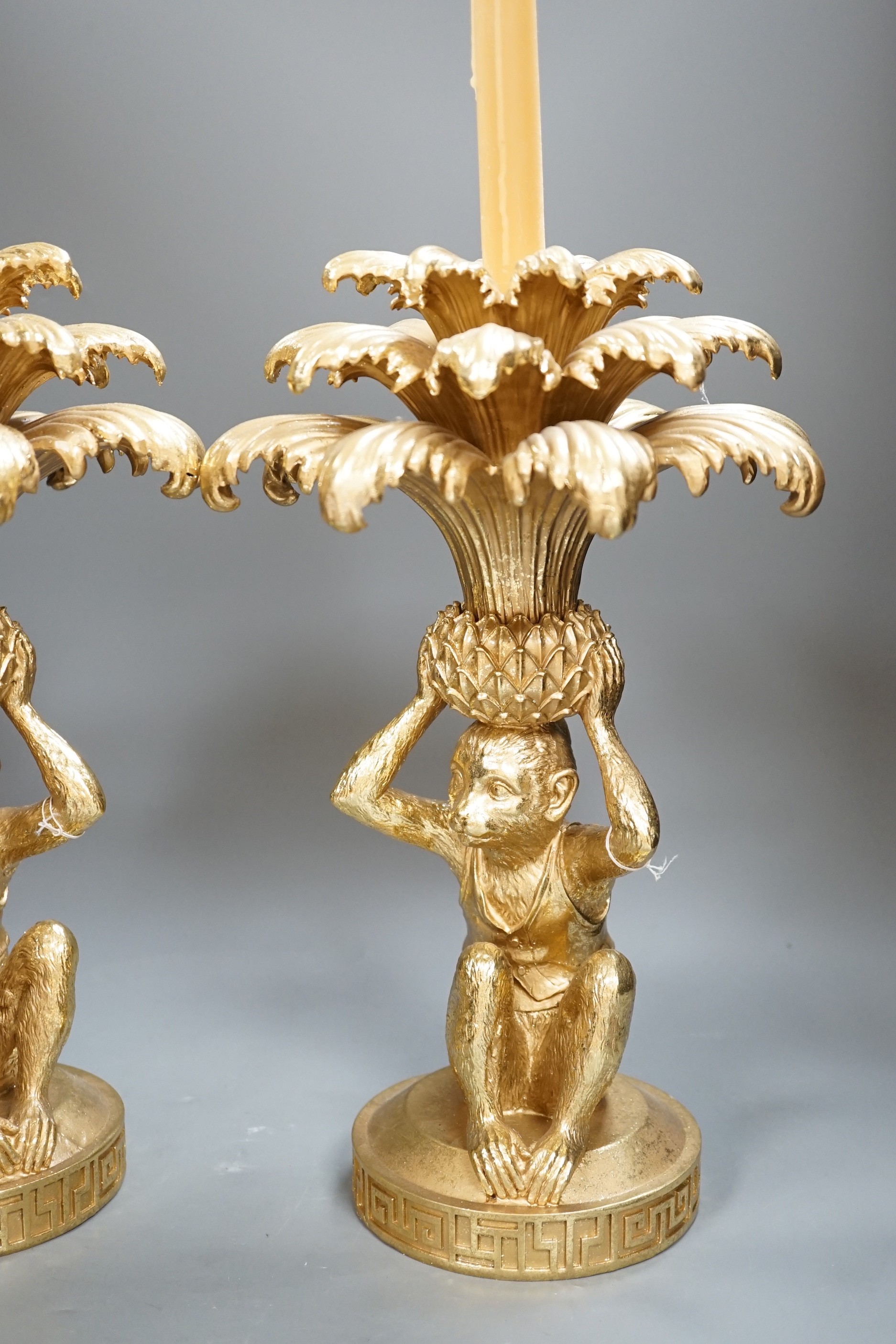 A pair of gilt resin ‘monkey and pineapple’ candlesticks. 37cm tall